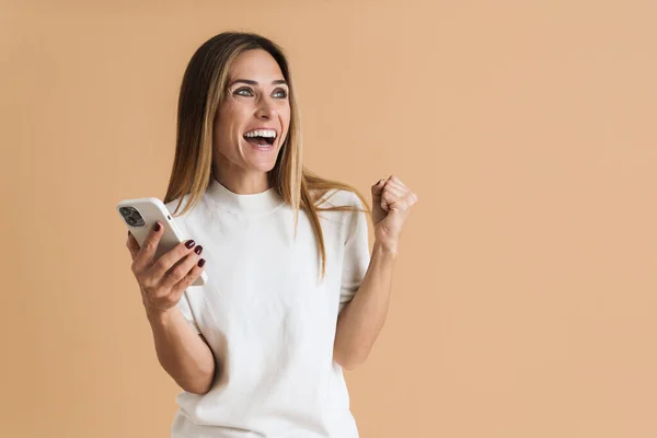 White Mid Woman Making Winner Gesture Using Cellphone Isolated Beige — Fotografia de Stock