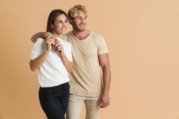 White couple wearing t-shirts hugging and smiling isolated over beige background