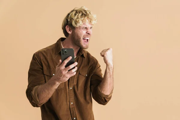 White Blonde Man Making Winner Gesture While Using Cellphone Isolated — 图库照片
