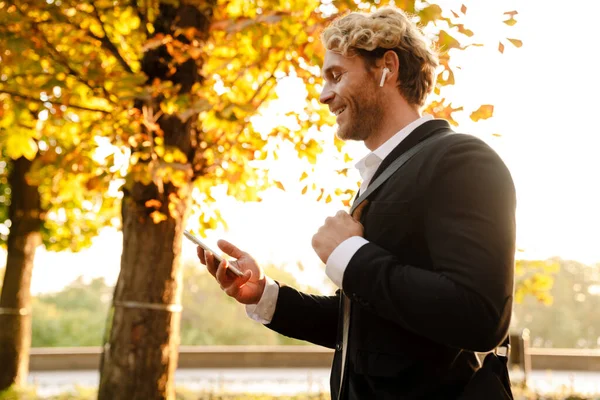 Blonde Man Using Earphones Mobile Phone While Walking Autumn Park — Foto Stock