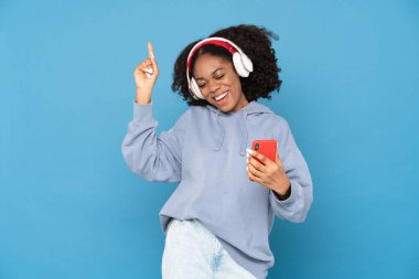 Genç siyahi kadın cep telefonu kullanırken, beyaz arka plan üzerinden yukarı doğru işaret ediyor.