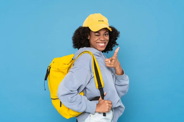 Black Woman Backpack Winking Pointing Finger Camera Isolated Blue Background — Stockfoto