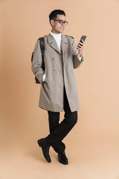 Young Middle Eastern Man Wearing Coat Using Mobile Phone Isolated — Stockfoto