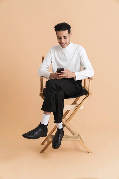 Young Middle Eastern Man Using Cellphone While Sitting Chair Isolated — Stock Photo, Image