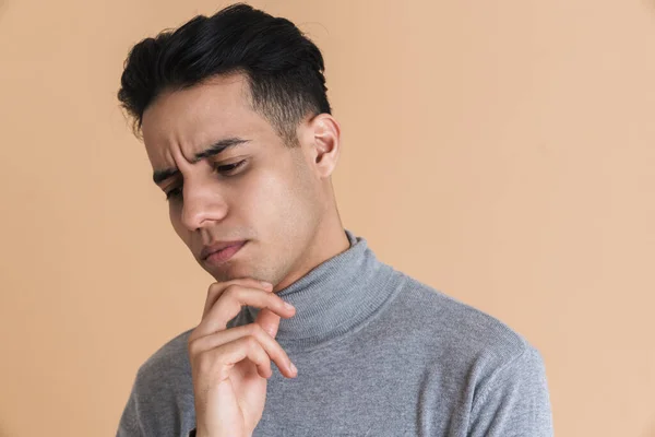 Young Puzzled Man Frowning While Holding His Chin Isolated Beige — Stockfoto
