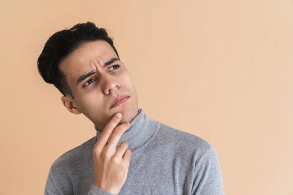 Young Puzzled Man Frowning While Holding His Chin Isolated Beige — 스톡 사진