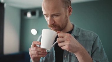 Güzel sarışın adam kibrit içer ve eve bakar.