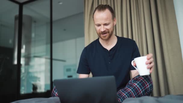 Smiling Blond Man Holding Cup Looking Laptop While Sitting Home — Stock Video