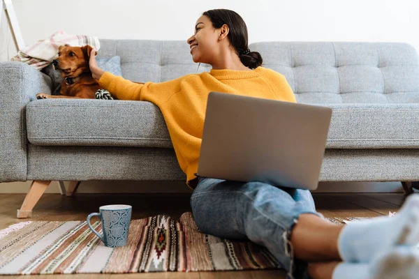 Young Hispanic Woman Petting Her Dog While Working Laptop Home — Stockfoto