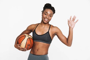 Kulaklıklı siyahi sporcu kadın, beyaz arka planda basketbolla poz verirken işaret veriyor.