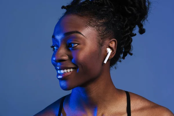 Black Young Sportswoman Earphones Smiling Looking Aside Isolated Blue Background — Stockfoto
