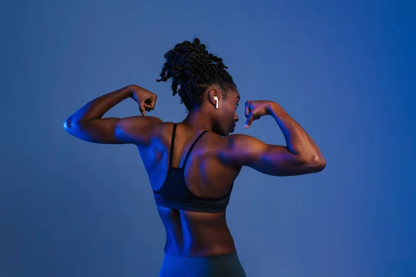 Black Young Sportswoman Earphones Showing Her Biceps Isolated Blue Background — Fotografia de Stock