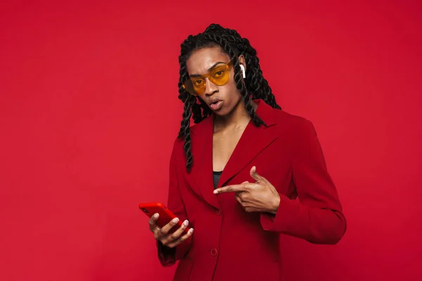 Black Young Woman Earphones Pointing Finger Her Cellphone Isolated Red — Stock fotografie