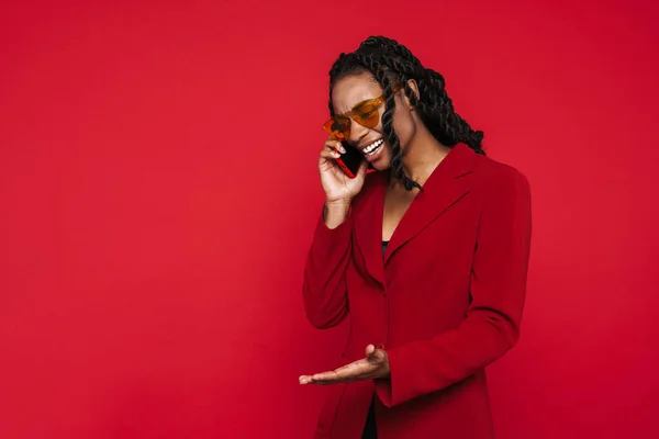 Black Young Woman Gesturing While Talking Cellphone Isolated Red Background — Stockfoto