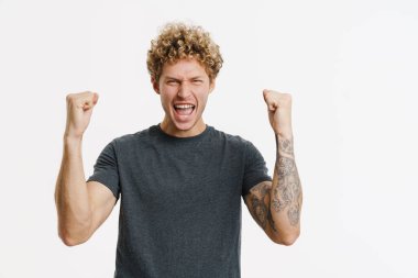 Genç sarışın adam çığlık atarken, beyaz duvarın üzerinde izole edilmiş bir jest yapıyor.