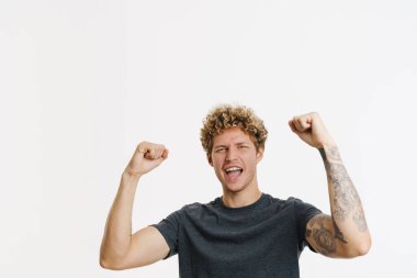 Genç sarışın adam çığlık atarken, beyaz duvarın üzerinde izole edilmiş bir jest yapıyor.