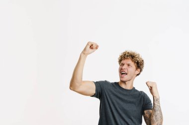 Genç sarışın adam çığlık atarken, beyaz duvarın üzerinde izole edilmiş bir jest yapıyor.