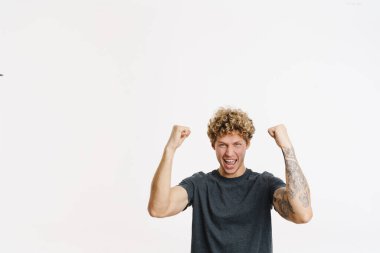 Genç sarışın adam çığlık atarken, beyaz duvarın üzerinde izole edilmiş bir jest yapıyor.