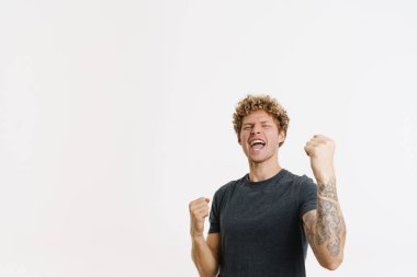 Genç sarışın adam çığlık atarken, beyaz duvarın üzerinde izole edilmiş bir jest yapıyor.