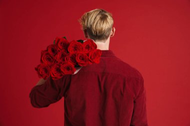 Sarışın sakallı adam kırmızı arka planda sakallı gül buketi ile poz veriyor.