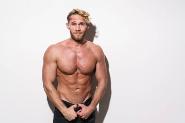 Beyaz tişörtsüz, ruj izi olan beyaz adam gülümseyen ve beyaz duvarın üzerinden izole edilmiş kameraya bakan.