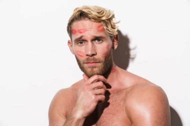 Ruj izi olan beyaz gömleksiz bir adam beyaz duvarın üzerinden izole edilmiş kameraya bakıyor.