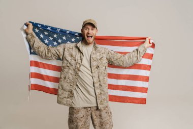 White military man screaming while posing with american flag isolated over white wall