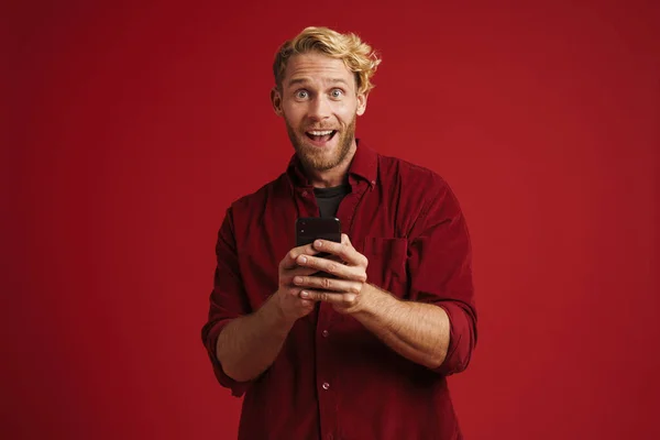 White Bearded Man Expressing Surprise Using Cellphone Isolated Red Wall — Stock fotografie