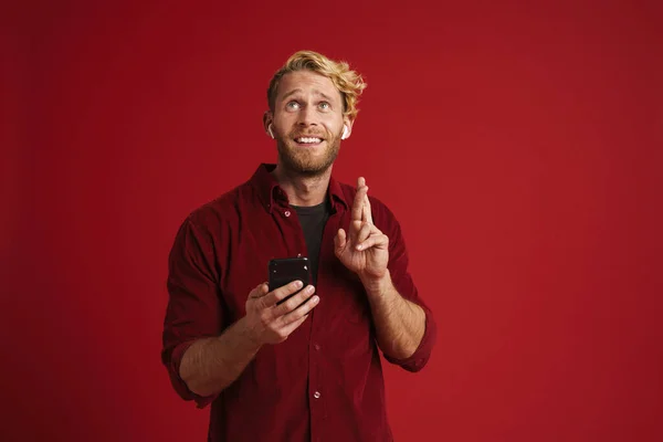 White Bearded Man Holding Fingers Crossed Using Cellphone Isolated Red —  Fotos de Stock
