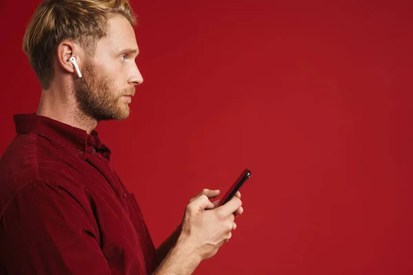 Blonde Man Listening Music Earphones Using Cellphone Isolated Red Wall — Stock Photo, Image