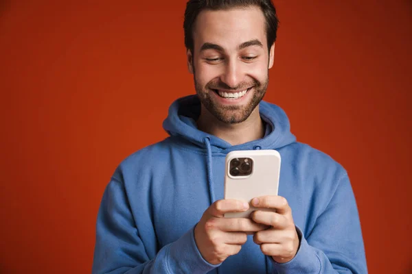 Young Bristle Man Smiling Using Mobile Phone Isolated Red Background — Φωτογραφία Αρχείου