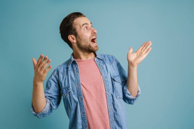 Genç kıllı adam mavi arka planda mahsur kaldığını belirterek hareket ediyor.