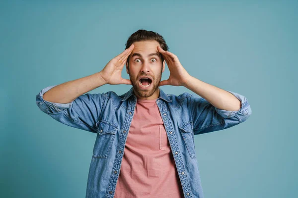 Young Man Holding His Head While Expressing Surprise Isolated Blue — Stockfoto