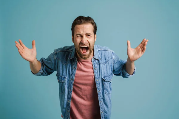 Young Furious Man Gesturing Screaming Camera Isolated Blue Background — Zdjęcie stockowe