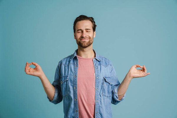Young bristle man meditating while making zen gesture isolated over blue background