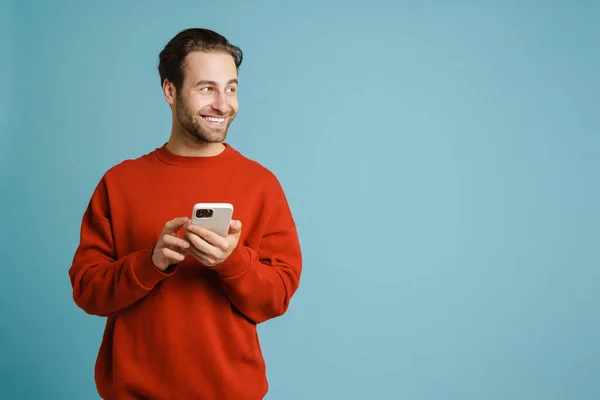 Young Bristle Man Smiling Using Mobile Phone Isolated Blue Background — Φωτογραφία Αρχείου
