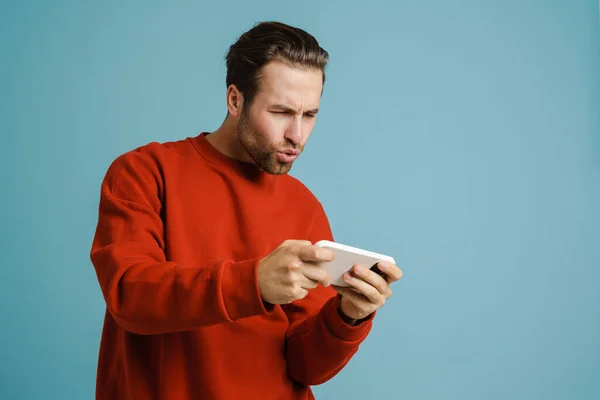 Young Excited Man Playing Online Game Mobile Phone Isolated Blue — Foto de Stock