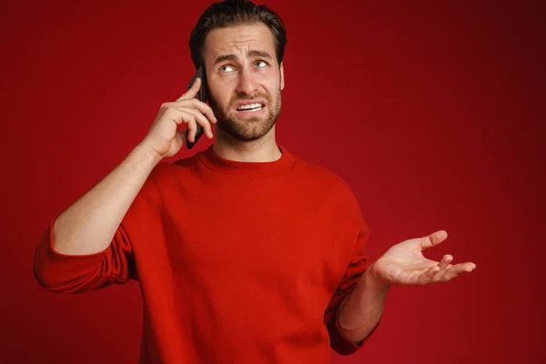 Young Bristle Man Holding Copyspace While Talking Cellphone Isolated Red — Stock Photo, Image