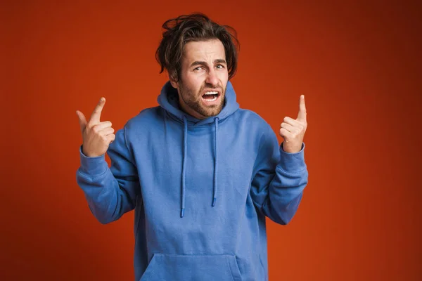 Young Disheveled Man Frowning Pointing Finger Upward Isolated Red Background — Stok fotoğraf