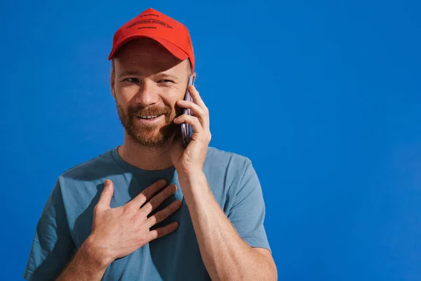 White Ginger Man Wearing Cap Gesturing While Talking Cellphone Isolated — стоковое фото