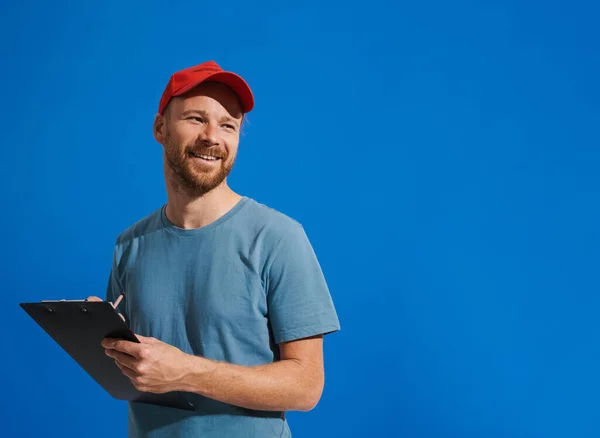 White Ginger Man Wearing Cap Smiling Writing Clipboard Isolated Blue — Fotografia de Stock