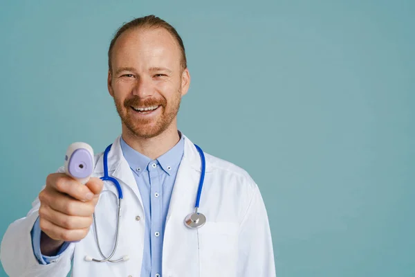 White Male Doctor Wearing Lab Coat Smiling Using Thermometer Isolated — ストック写真