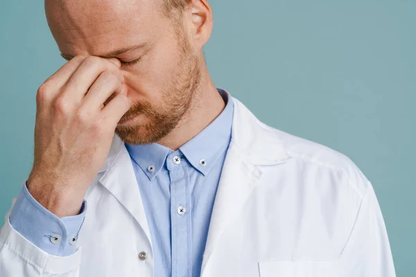 Unavený Mužský Lékař Bolestí Hlavy Pózovat Kameře Izolované Přes Modré — Stock fotografie
