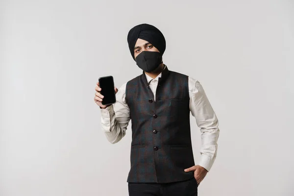 South Asian Man Wearing Turban Face Mask Showing Cellphone Isolated — 스톡 사진