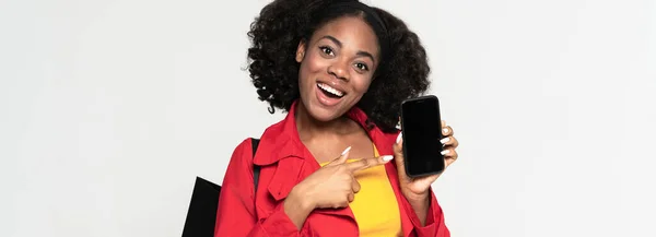 Чорна Жінка Вказує Пальцем Свій Мобільний Телефон Посміхаючись Ізольовано Білому — стокове фото