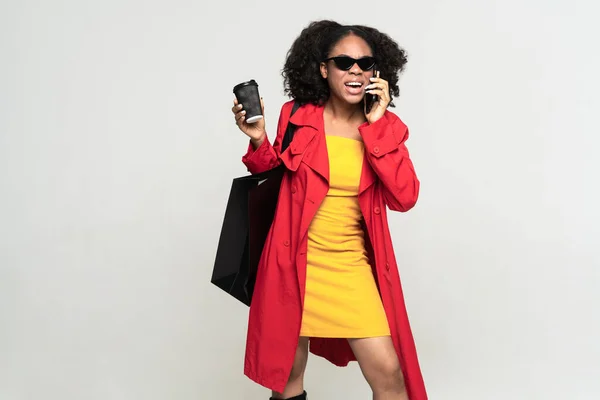 Czarna Kobieta Rozmawia Przez Telefon Podczas Pozowania Torbą Zakupy Izolowane — Zdjęcie stockowe