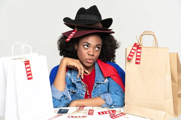 Black Puzzled Woman Wearing Hats Posing Shopping Bags Isolated White — Stock Fotó