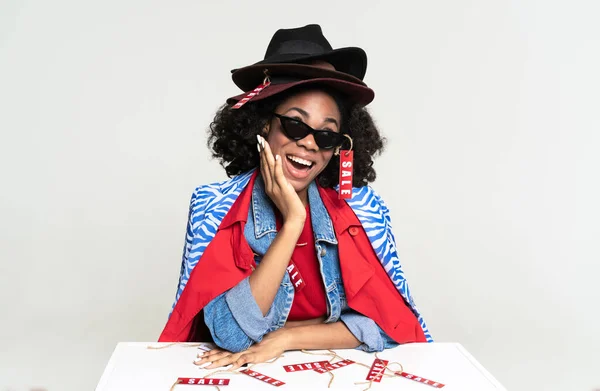 Young black woman smiling while posing with sale labels isolated over white background