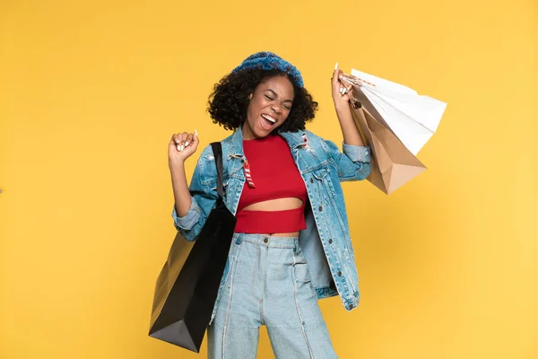 Black Woman Making Winner Gesture While Posing Shopping Bags Isolated — Stock Fotó