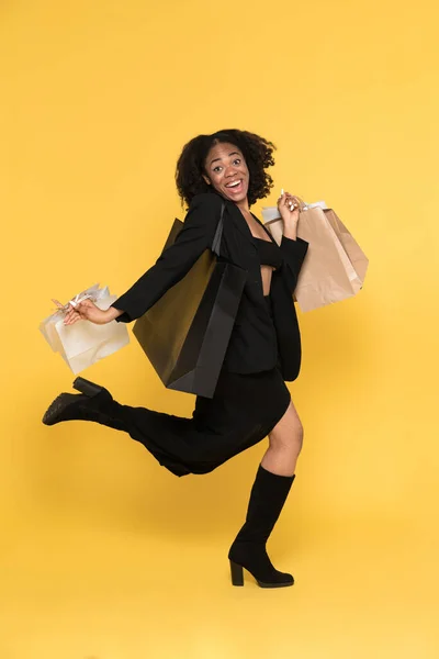 Young Black Woman Laughing While Running Shopping Bags Isolated Yellow — Stockfoto